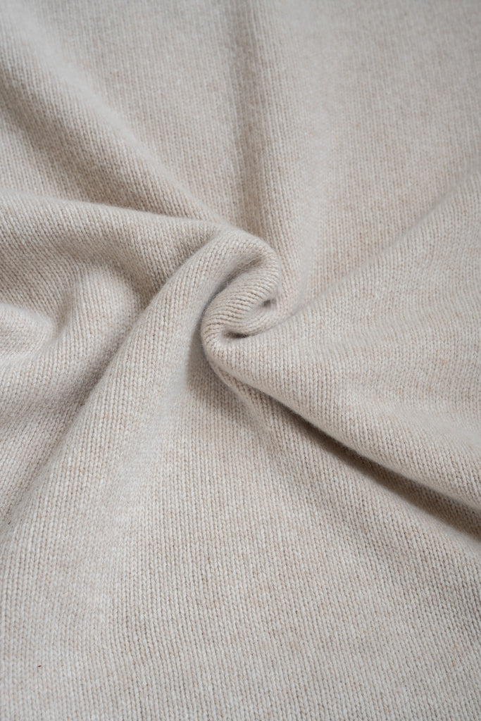 Beige plaid van 100% merinowol, 130 x 170 cm, glad gebreid, gefotografeerd als close-up van textuur en kleur.