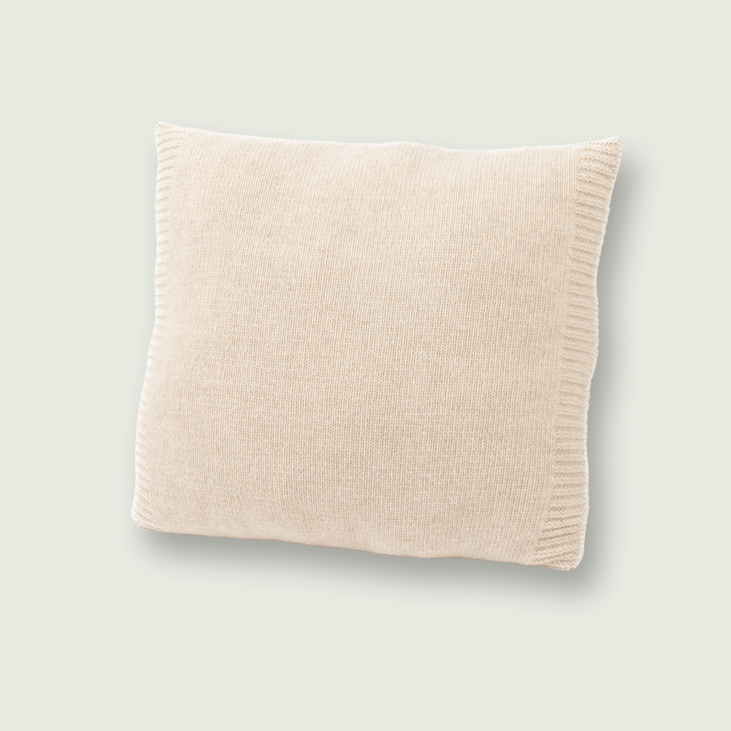 Gladgebreid beige sierkussen van 100% merinowol, 50 x 50 cm, gefotografeerd op een neutrale achtergrond.