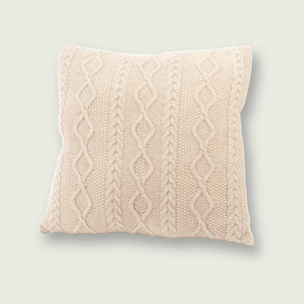 Beige sierkussen van 100% merinowol, 50 x 50 cm, met Aran-kabelpatroon, gefotografeerd op neutrale achtergrond.
