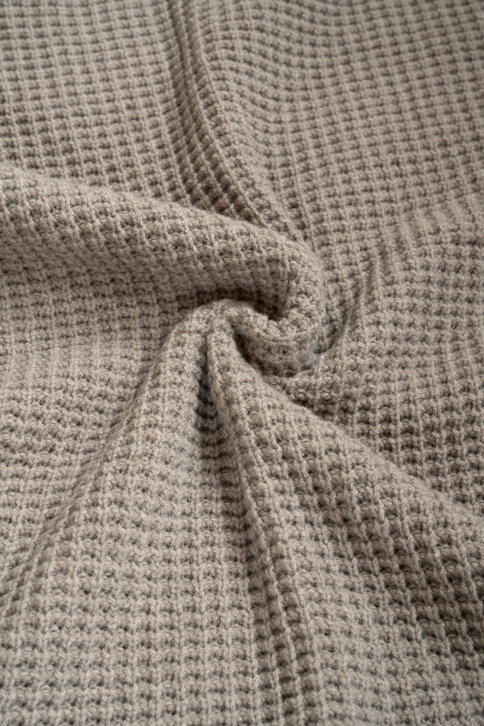 Bruine  plaid van 100% merinowol, 130 x 170 cm, met wafelpatroon, gefotografeerd als close-up van textuur en kleur.