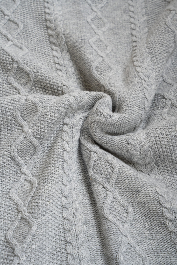 Grijze plaid van 100% merinowol, 130 x 170 cm, vlechtmotief, gefotografeerd als close-up van textuur en kleur.