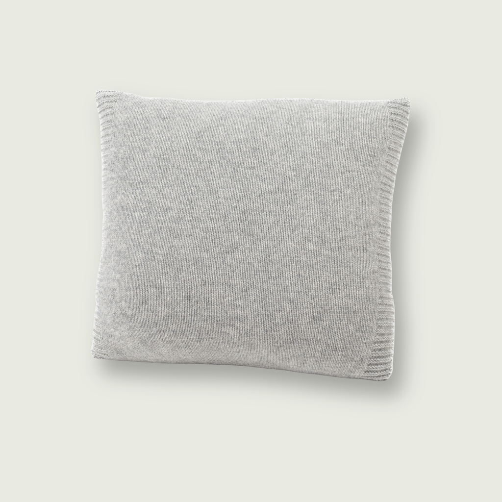Gladgebreid grijs sierkussen van 100% merinowol, 50 x 50 cm, gefotografeerd op neutrale achtergrond.