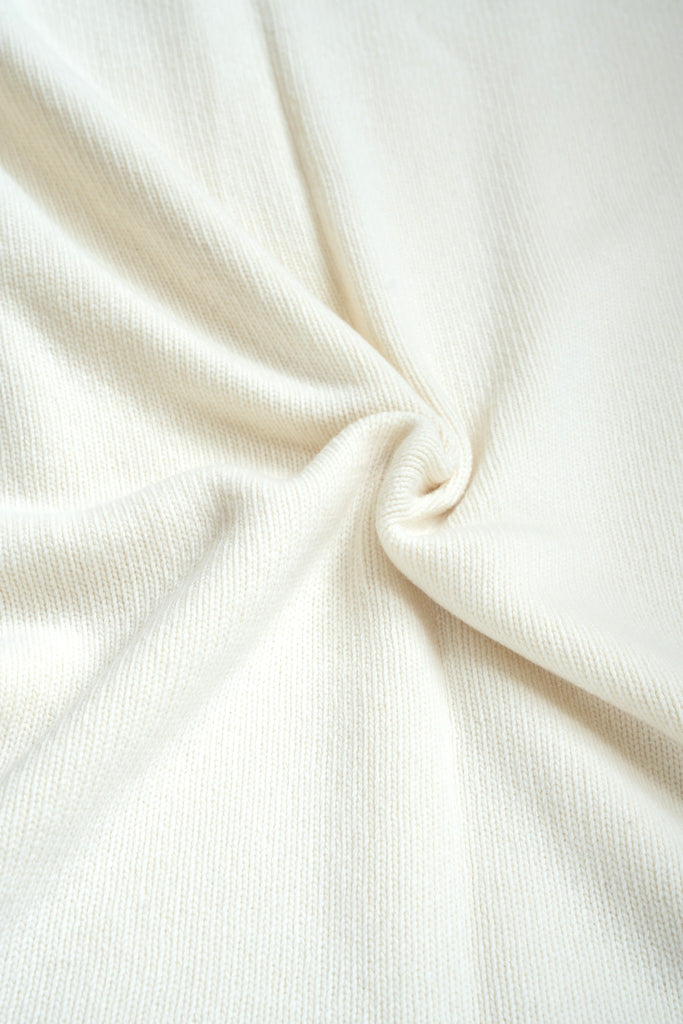 Witte plaid van 100% merinowol, 130 x 170 cm, glad gebreid, gefotografeerd als close-up van textuur en kleur.