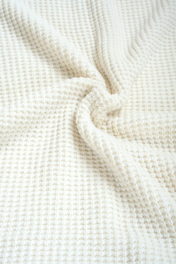Witte plaid van 100% merinowol, 130 x 170 cm, met wafelpatroon, gefotografeerd als close-up van textuur en kleur.